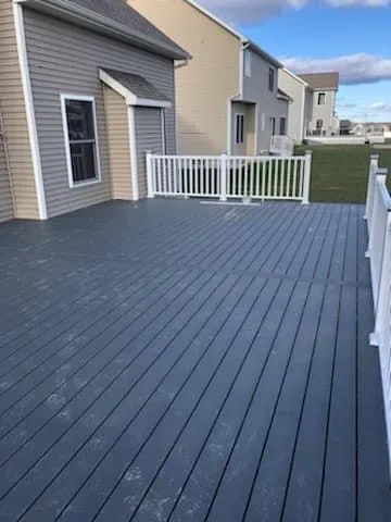 Gray composite deck with white railings in suburban backyard