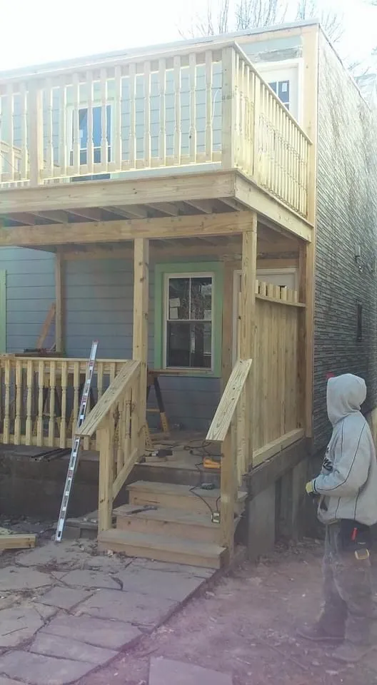 Second-story porch framing with ladder on stone patio