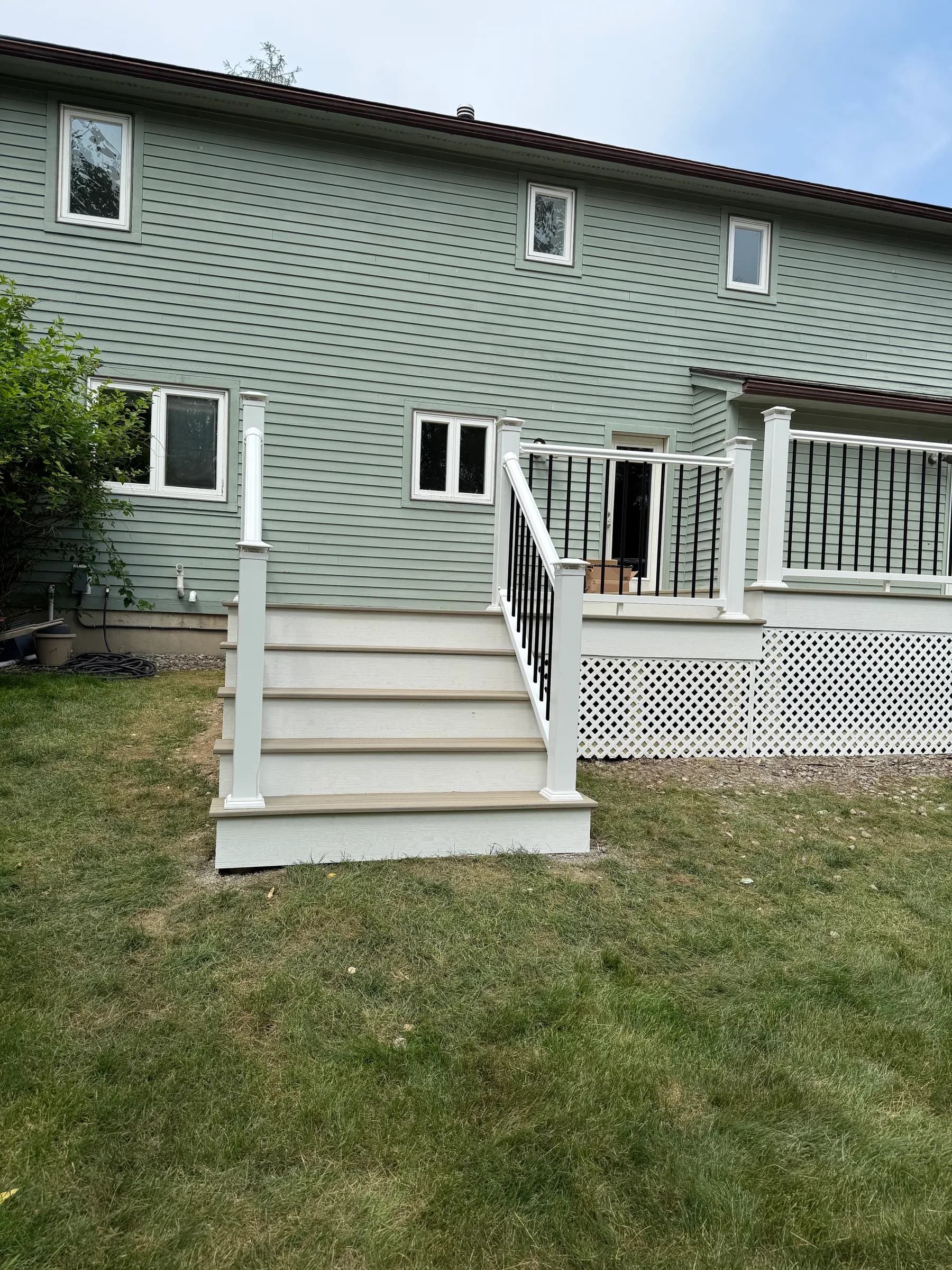 Side angle of deck with white stairs and lattice