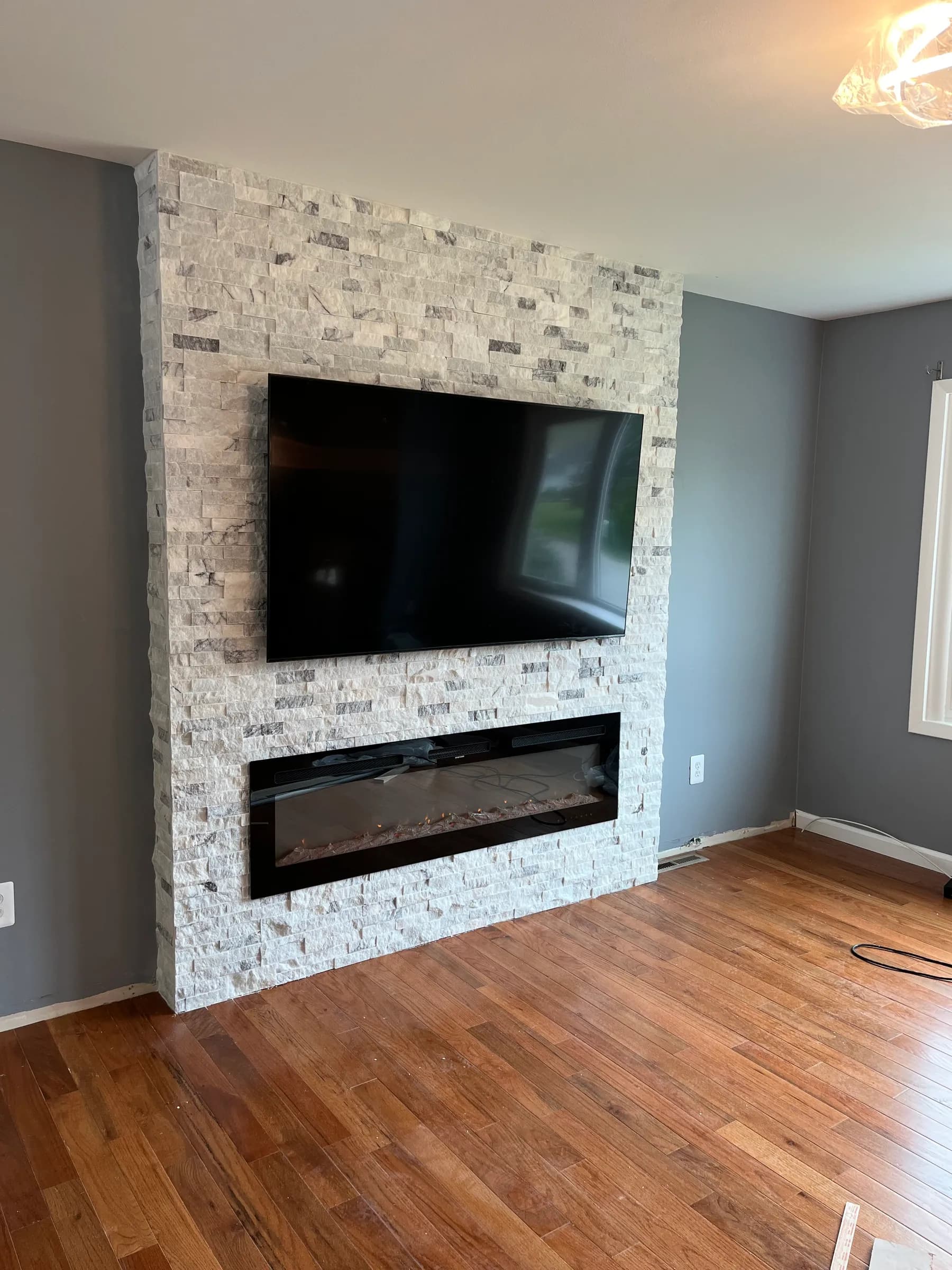 Tall stone feature wall with mounted TV and hardwood