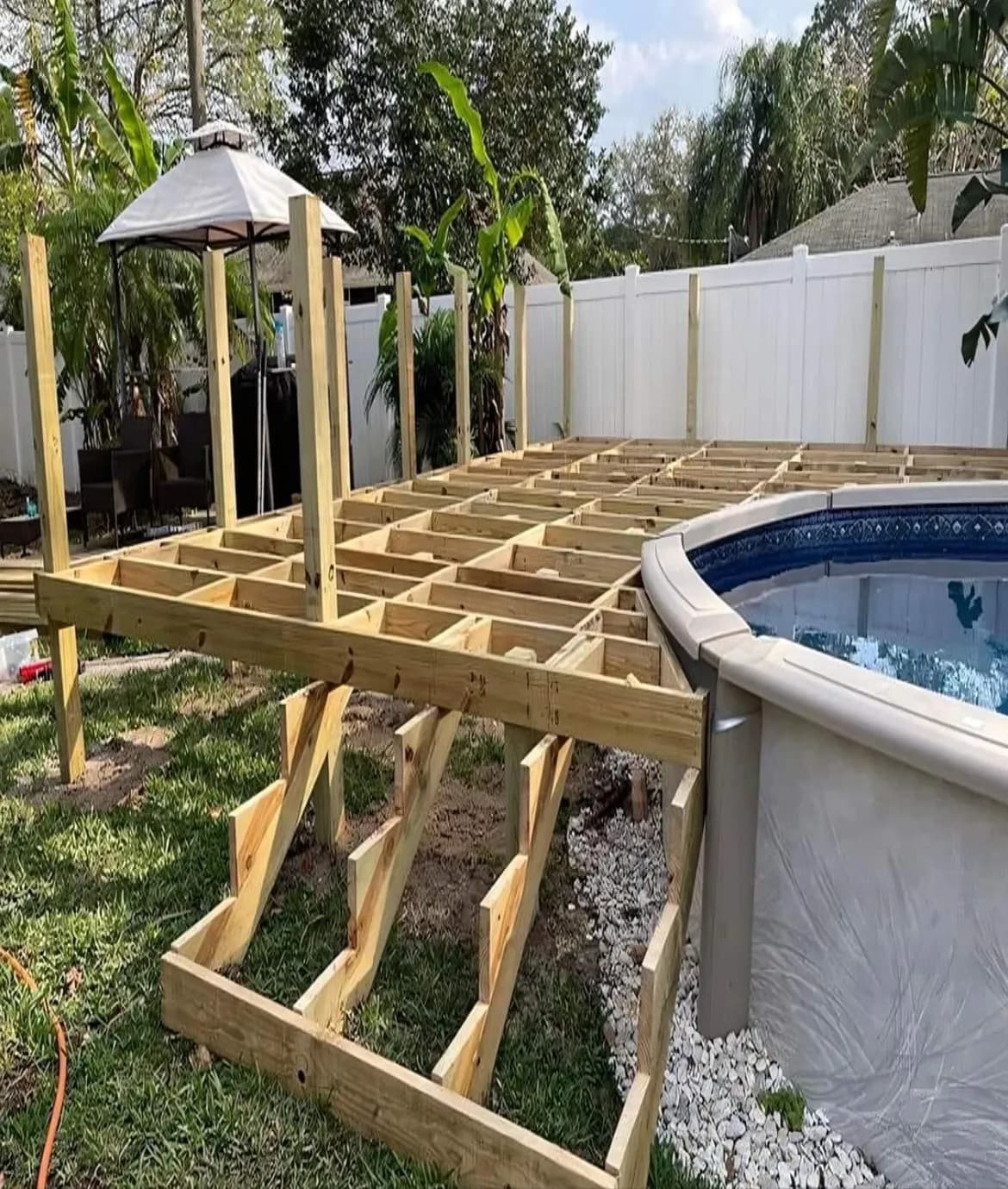 Deck framing around above-ground pool in tropical backyard