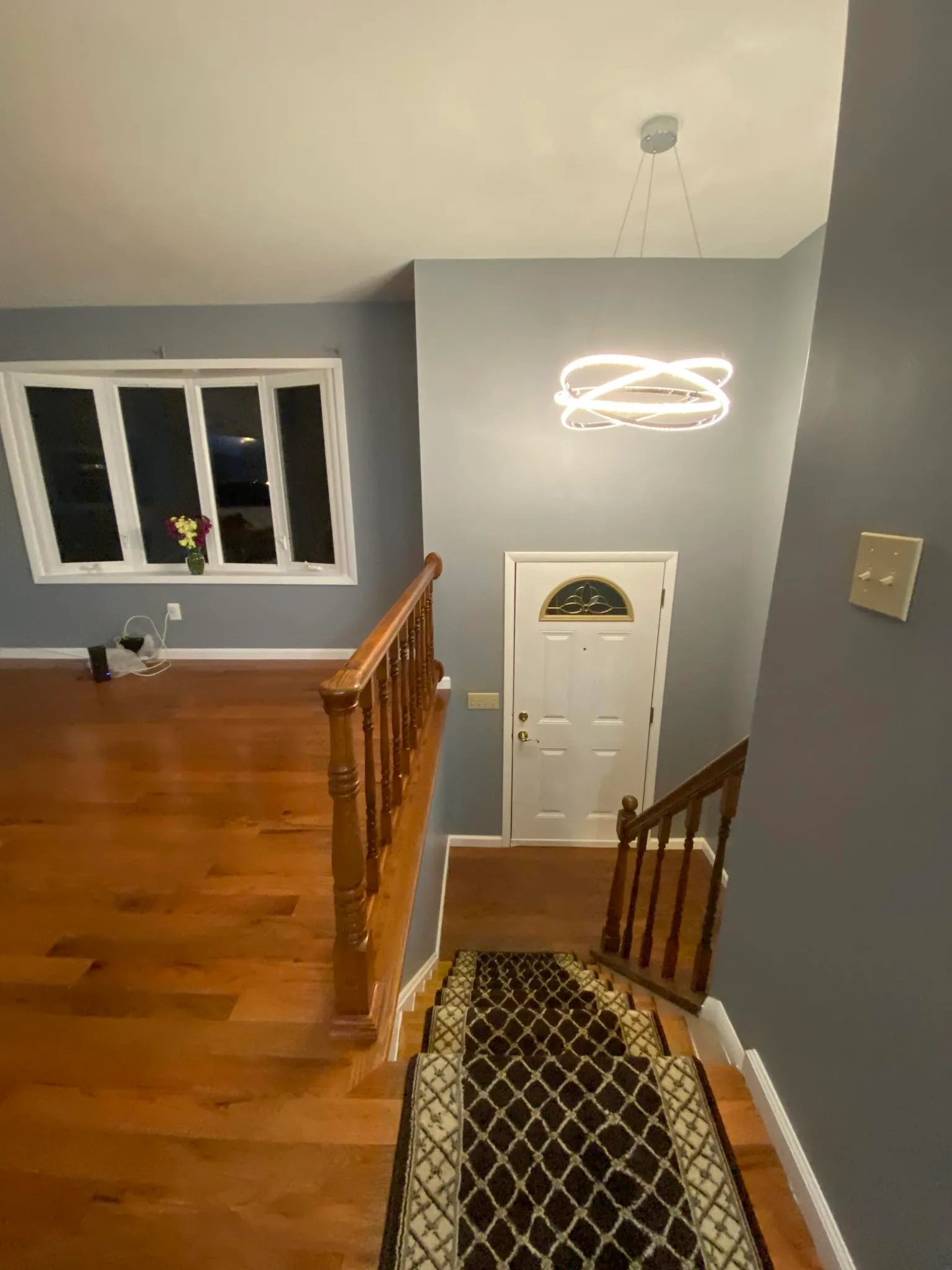 Foyer entry with runner, hardwood floor, and modern chandelier