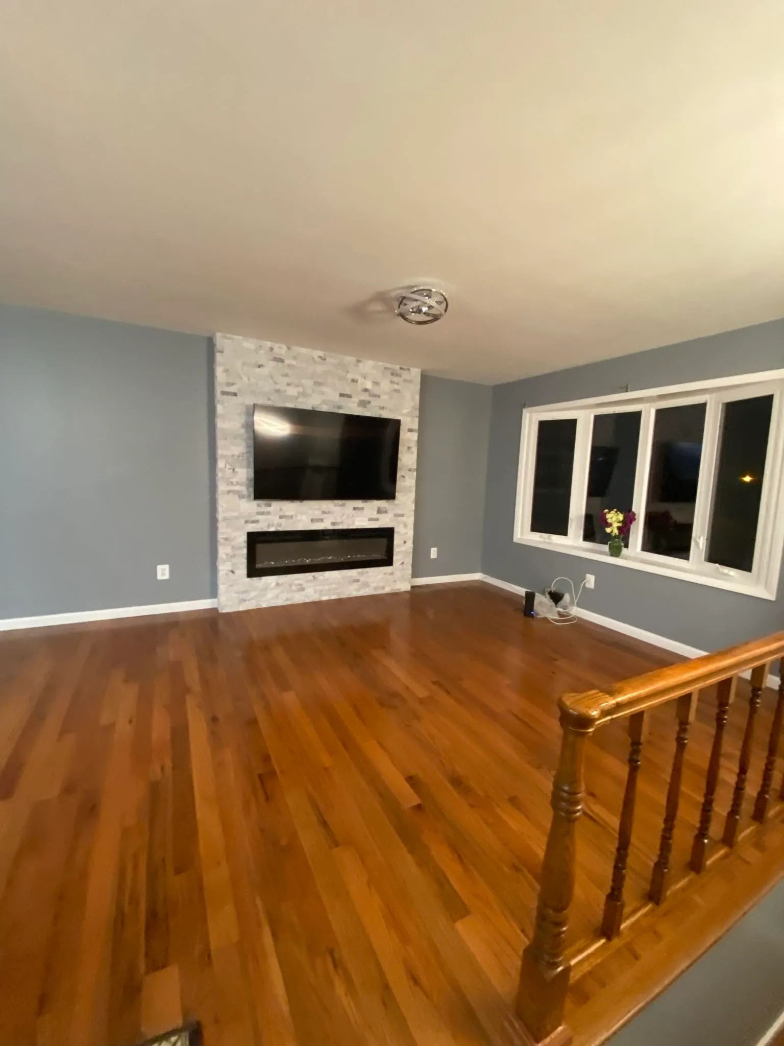 Open living room with hardwood flooring and stone fireplace feature wall