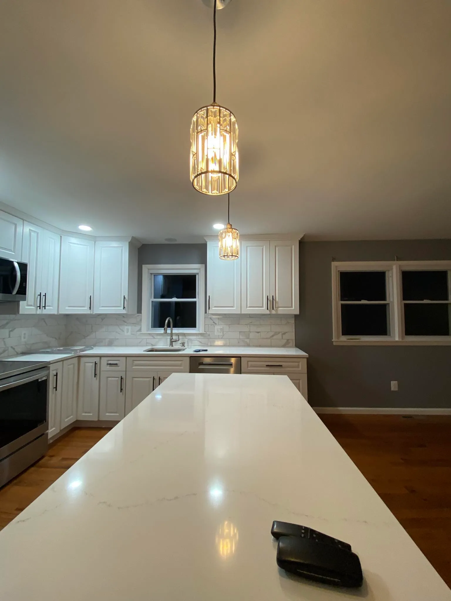 White kitchen with quartz counter, pendant, and new windows