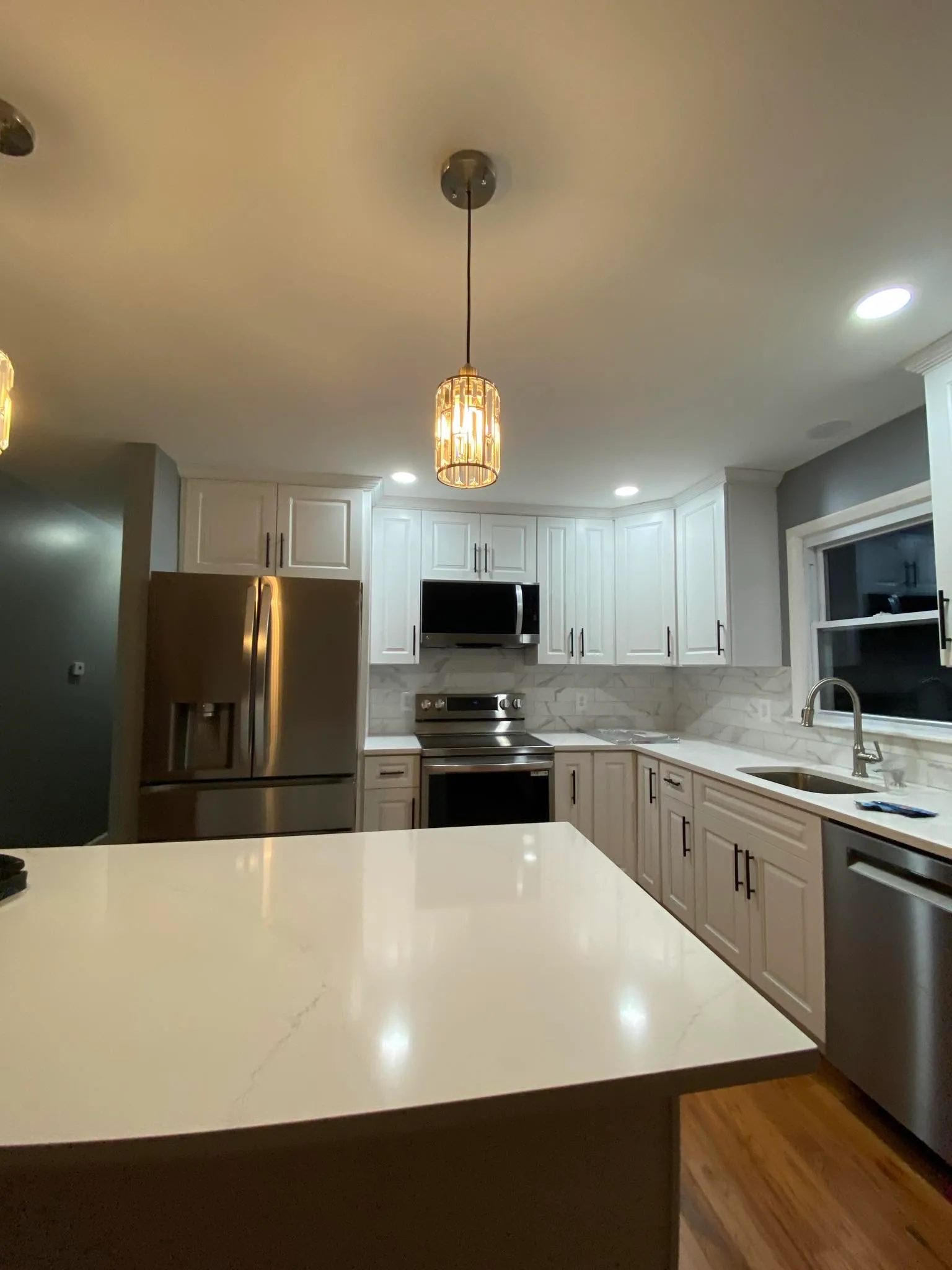 Kitchen with glass pendant chandeliers over waterfall island