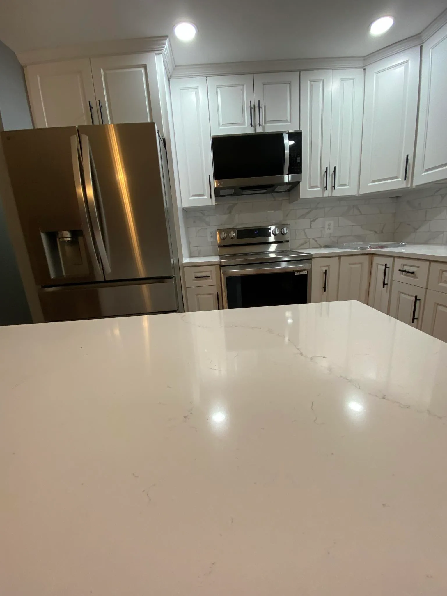White kitchen with quartz island countertop foreground