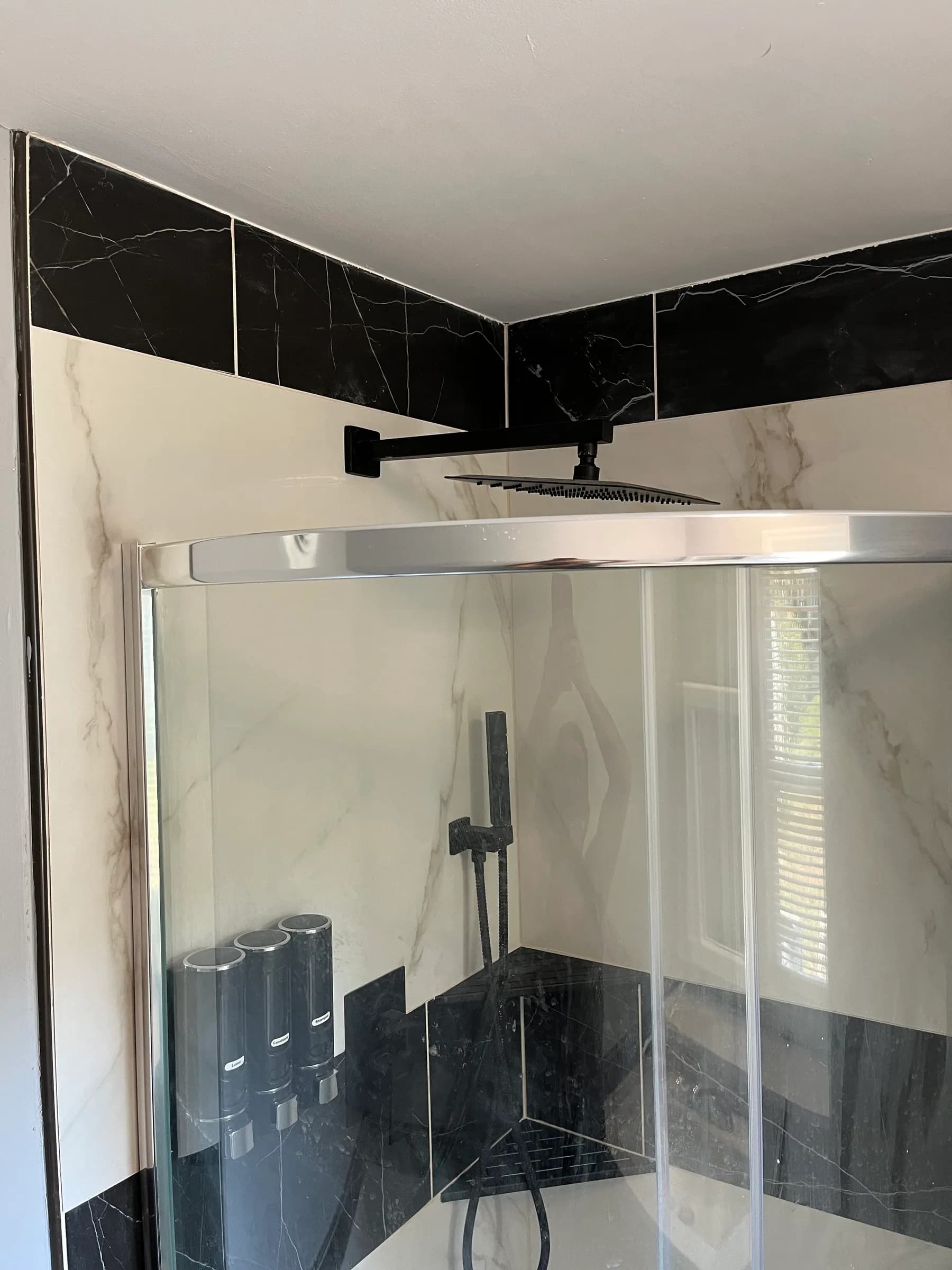 Glass shower door with black marble and handheld