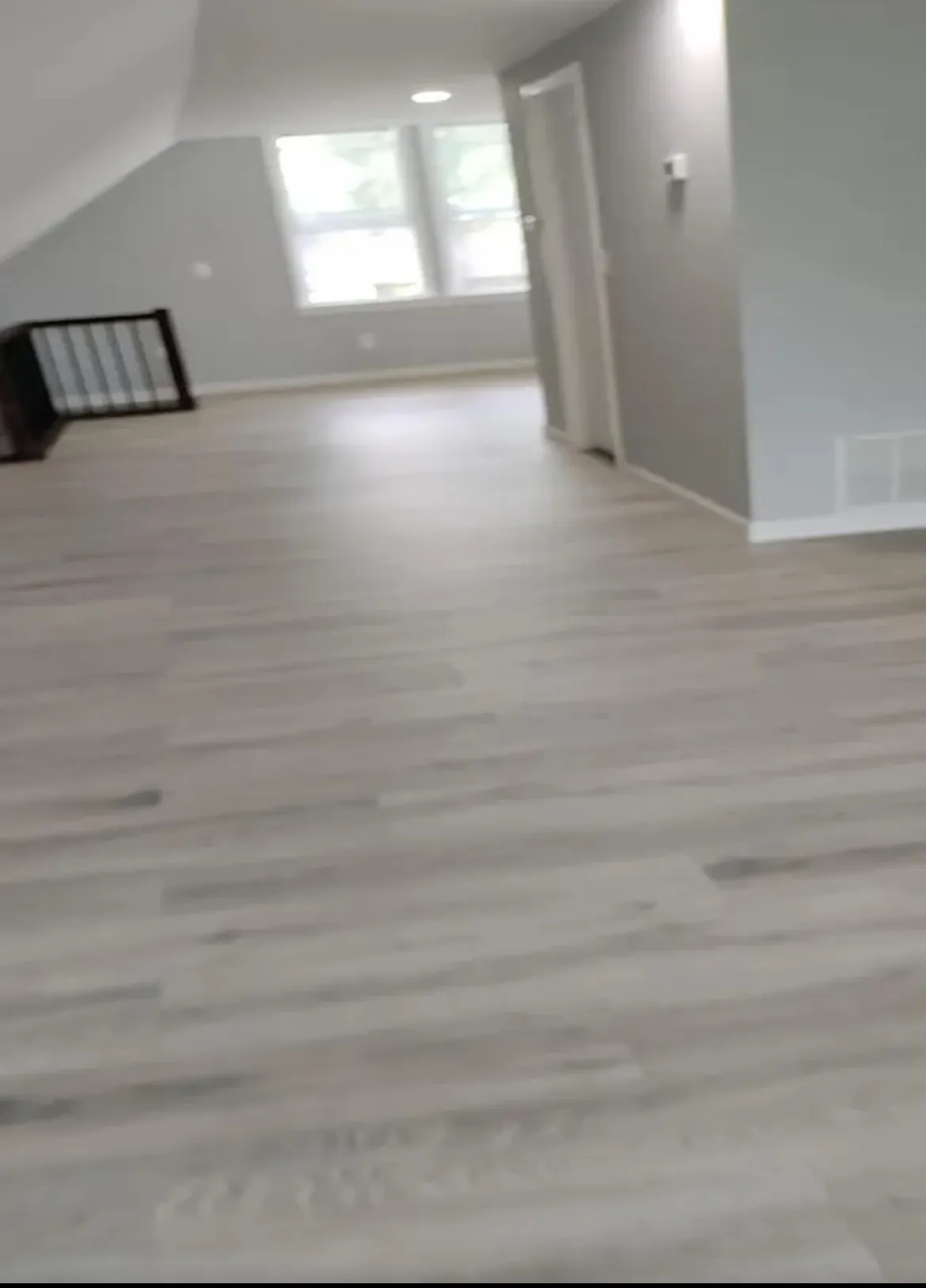 Open upstairs room with gray wood-look plank flooring