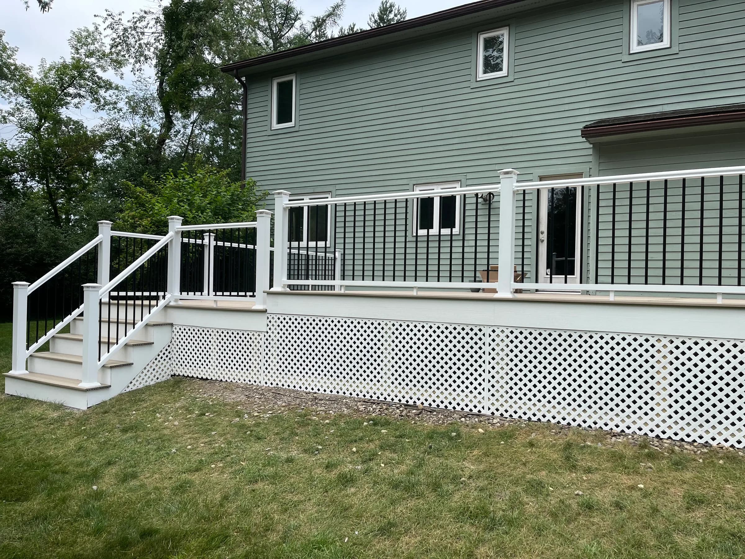 Side of green home with composite deck and lattice