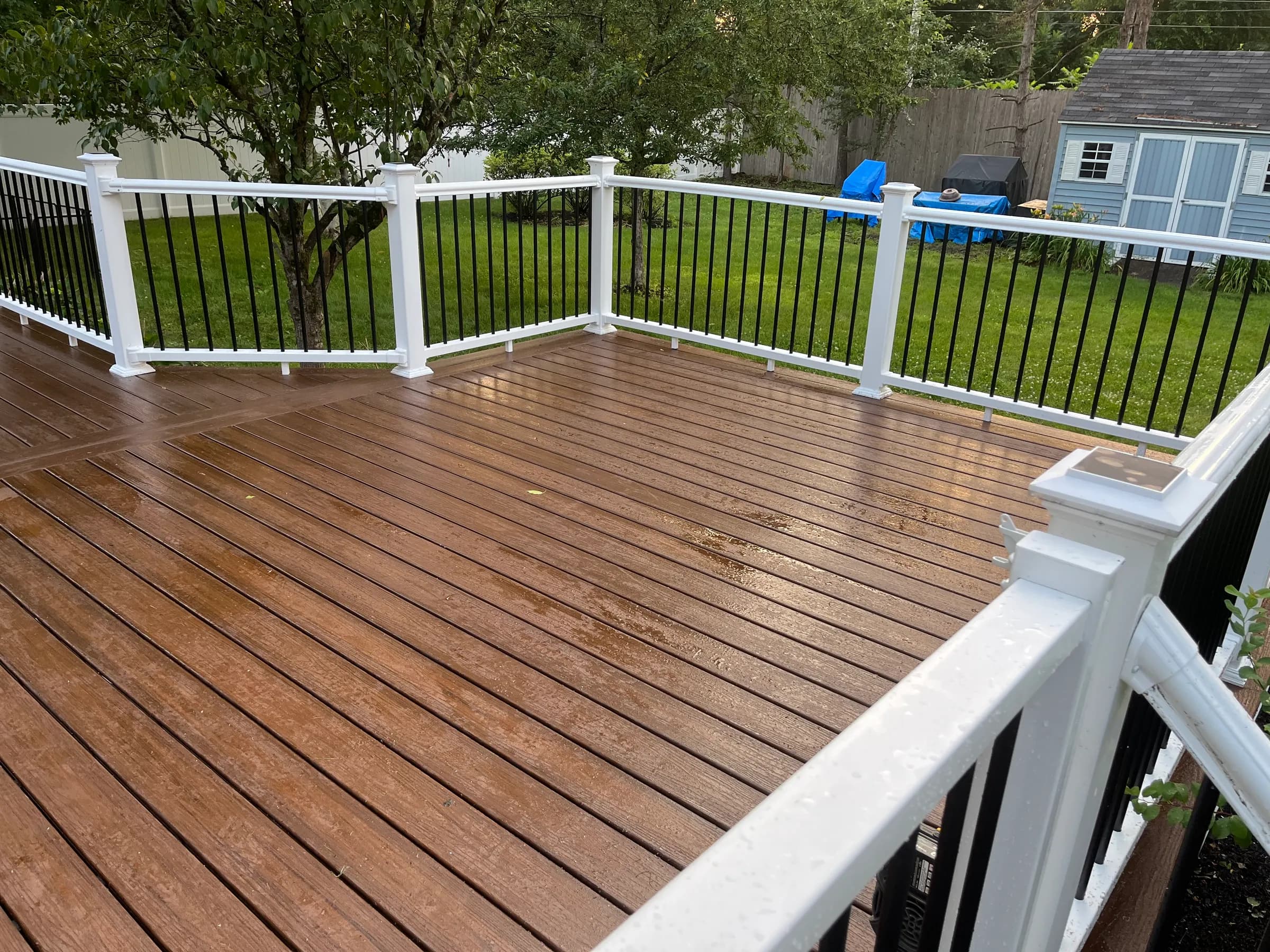 Brown composite deck with lush tree backdrop