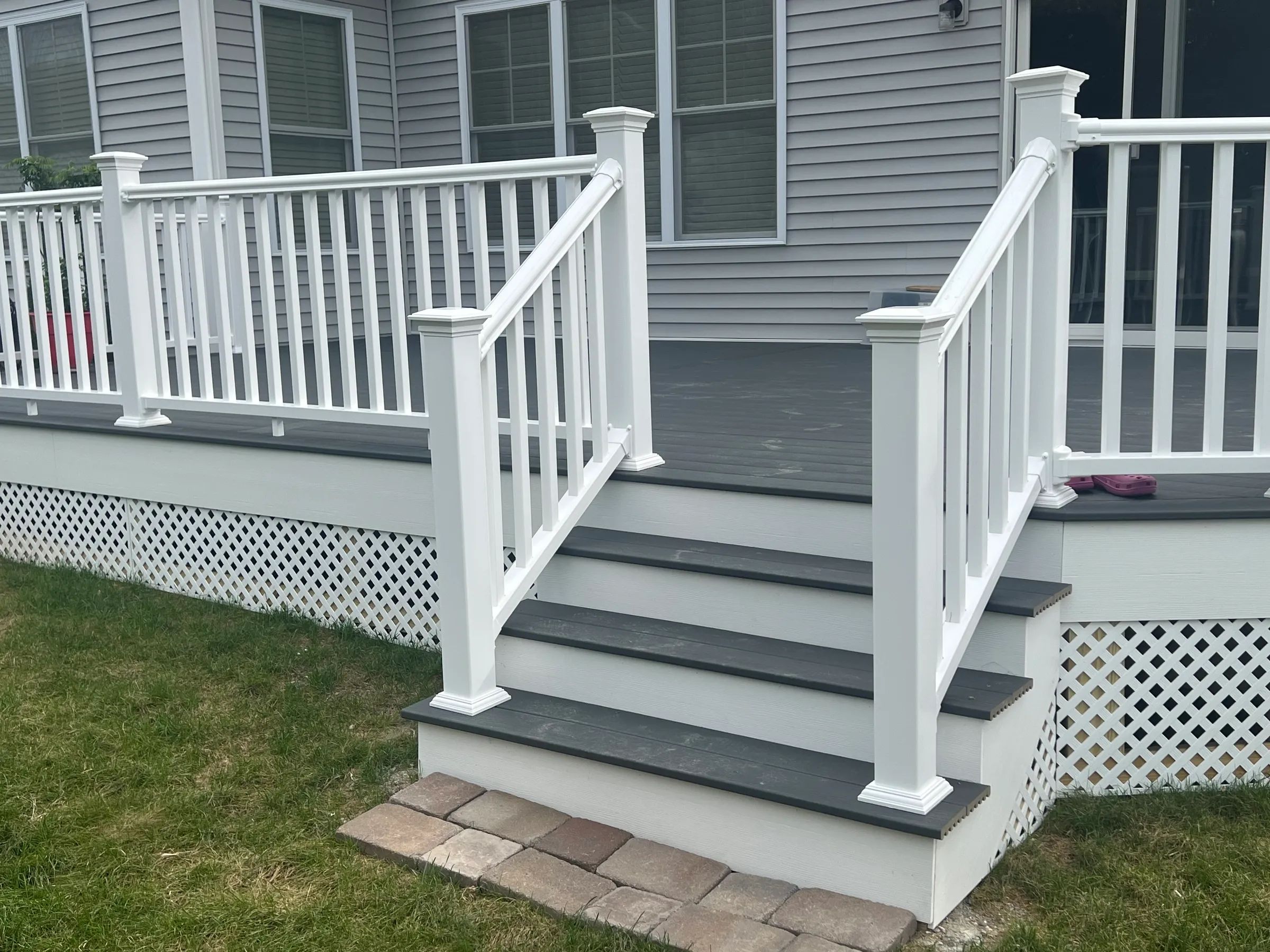 Gray deck with white stairs and paver landing
