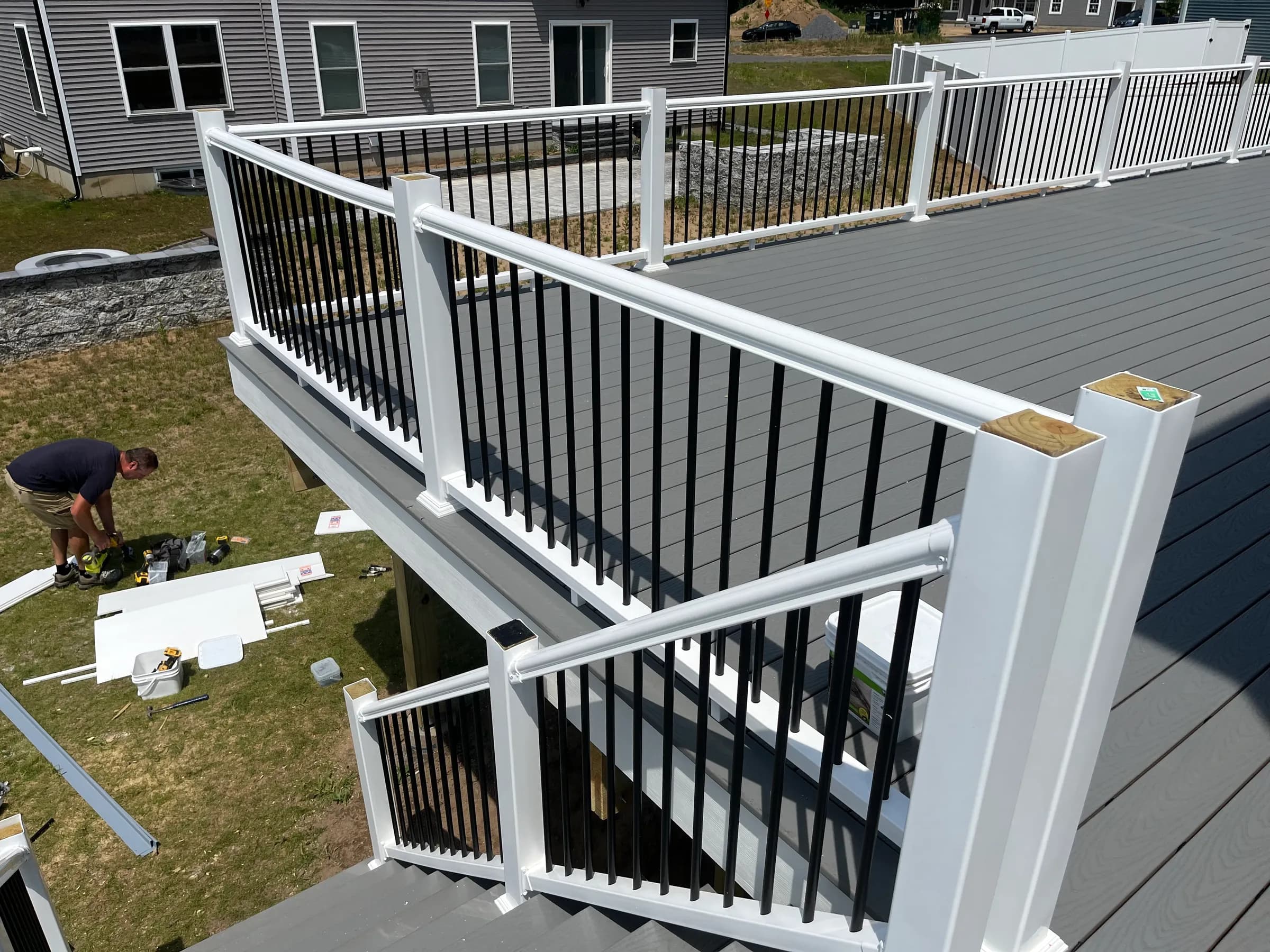 Gray deck corner with red potted plant and white rail