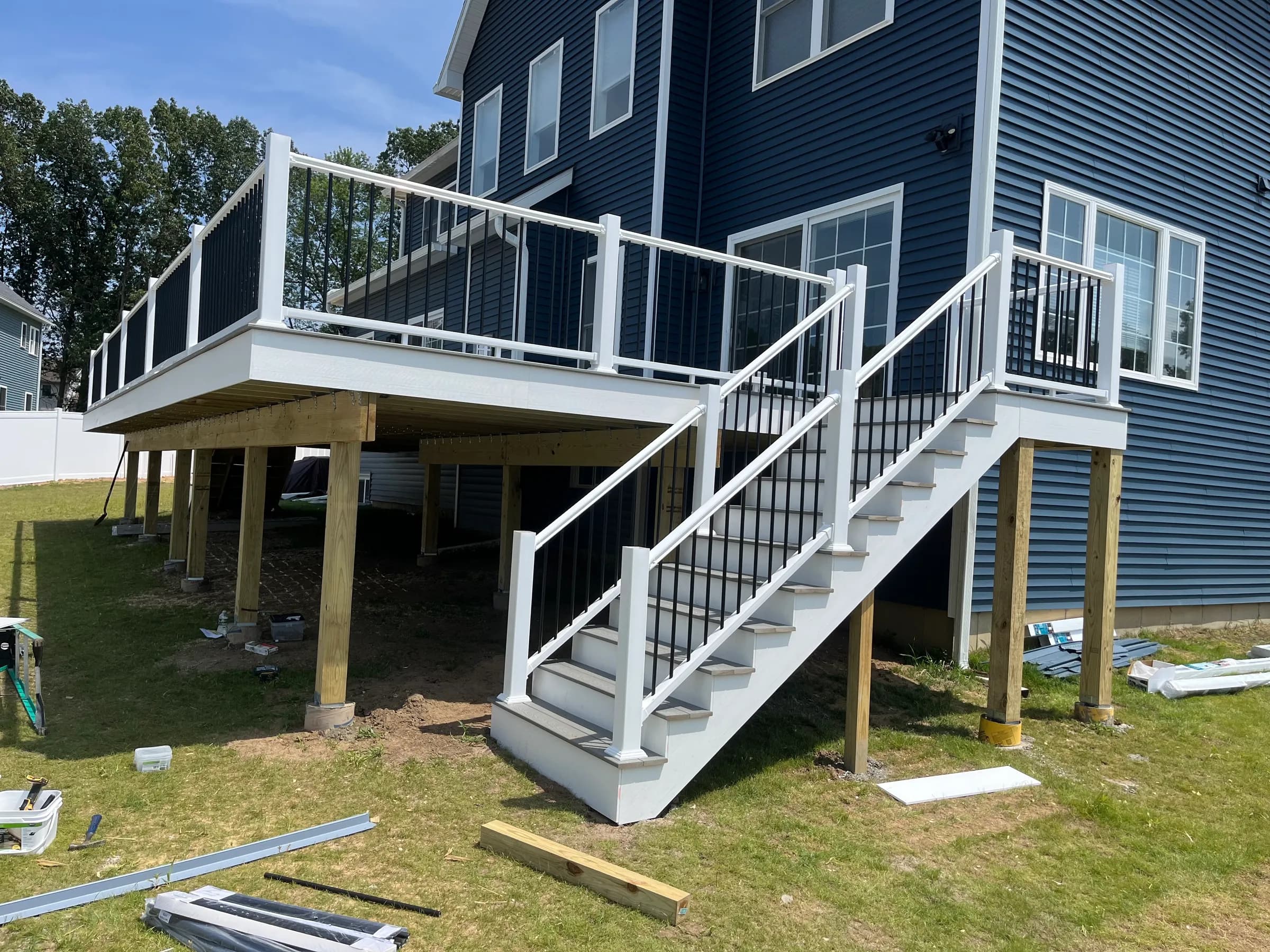 Elevated white composite deck with long stair run on navy blue two-story home