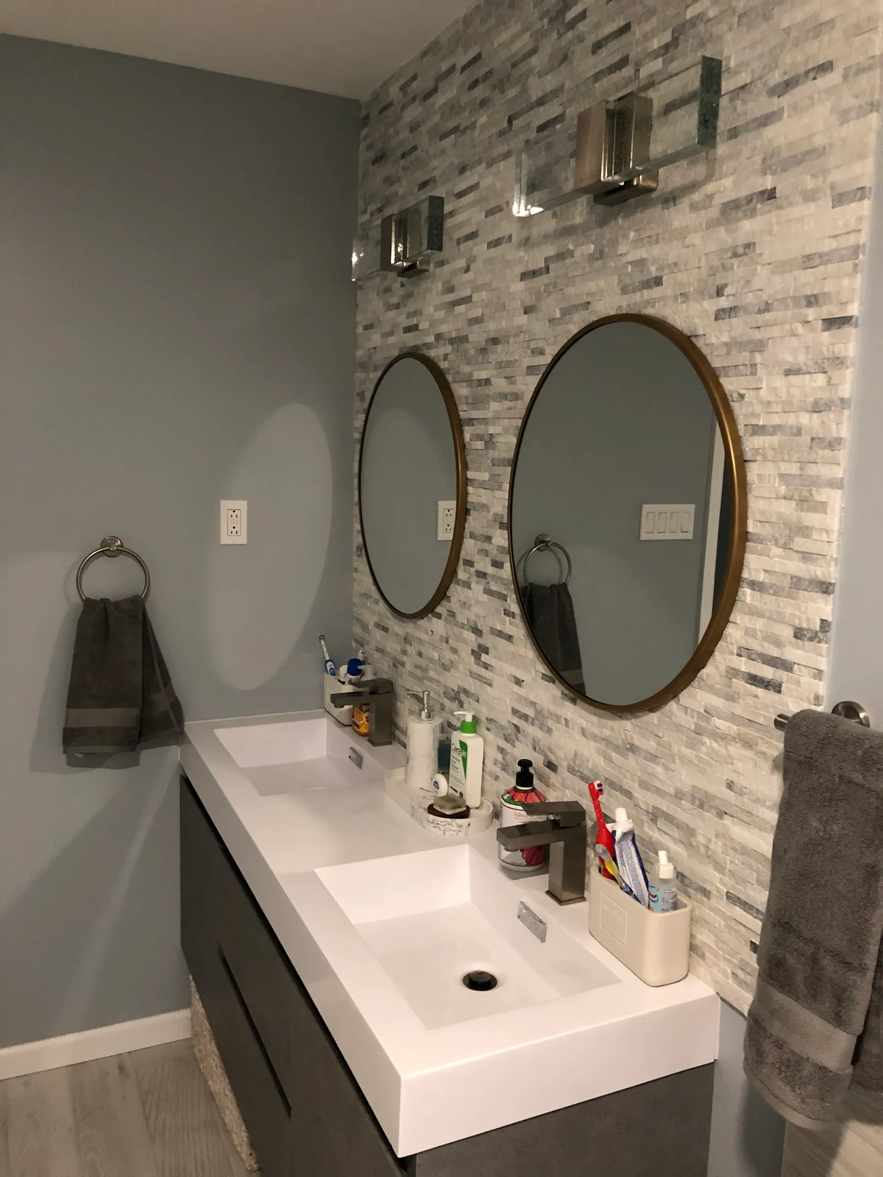 Double oval mirrors over sink with gray stacked stone wall