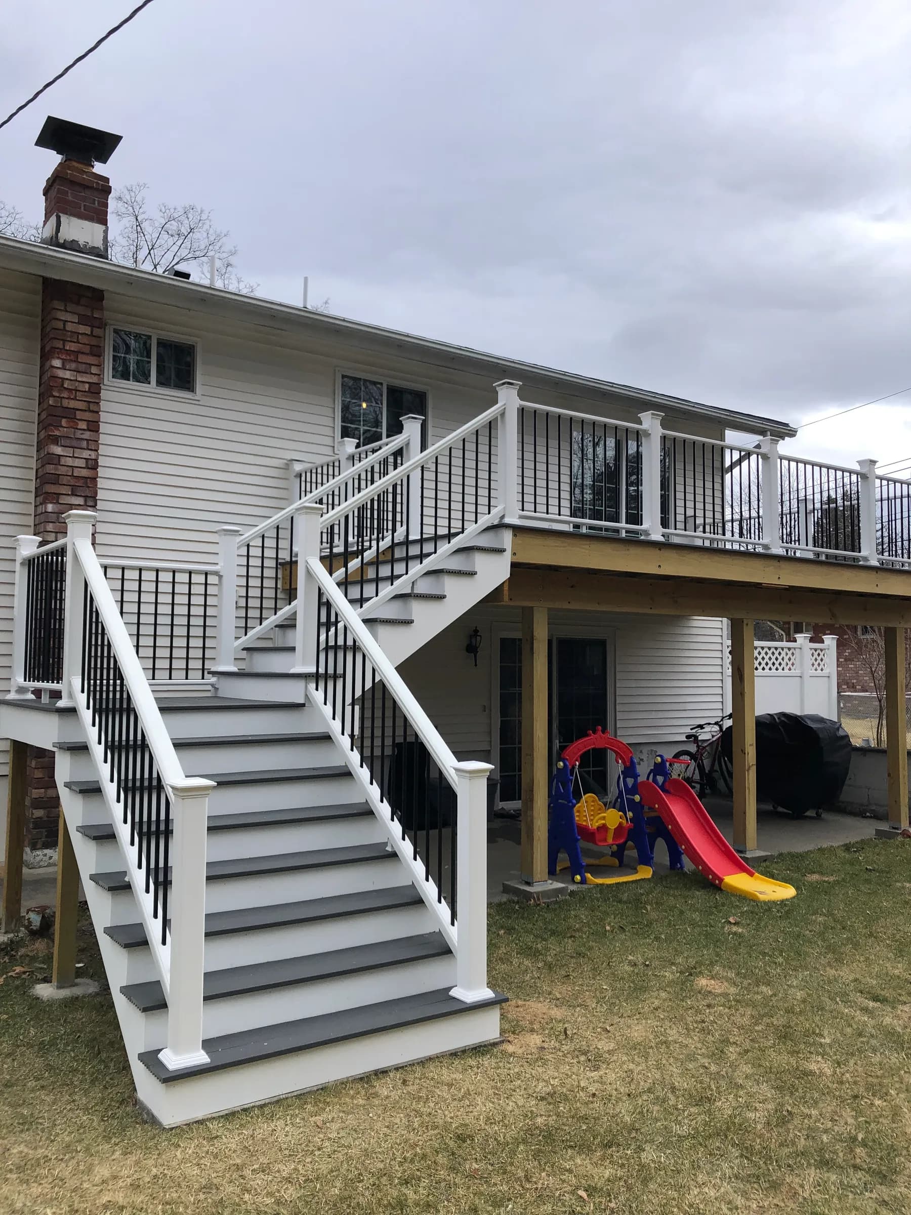 White deck with stairs to snowy lawn