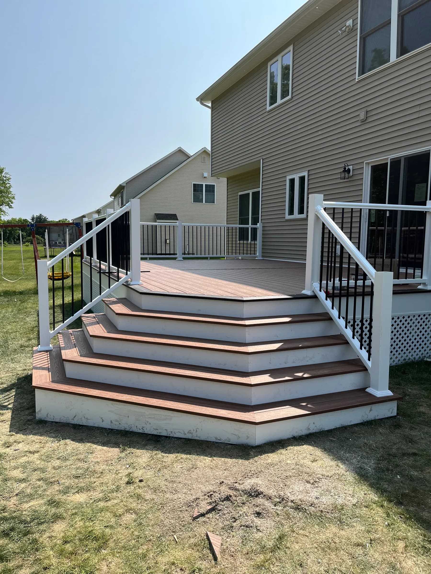 Tan composite deck with white pergola and black aluminum railings