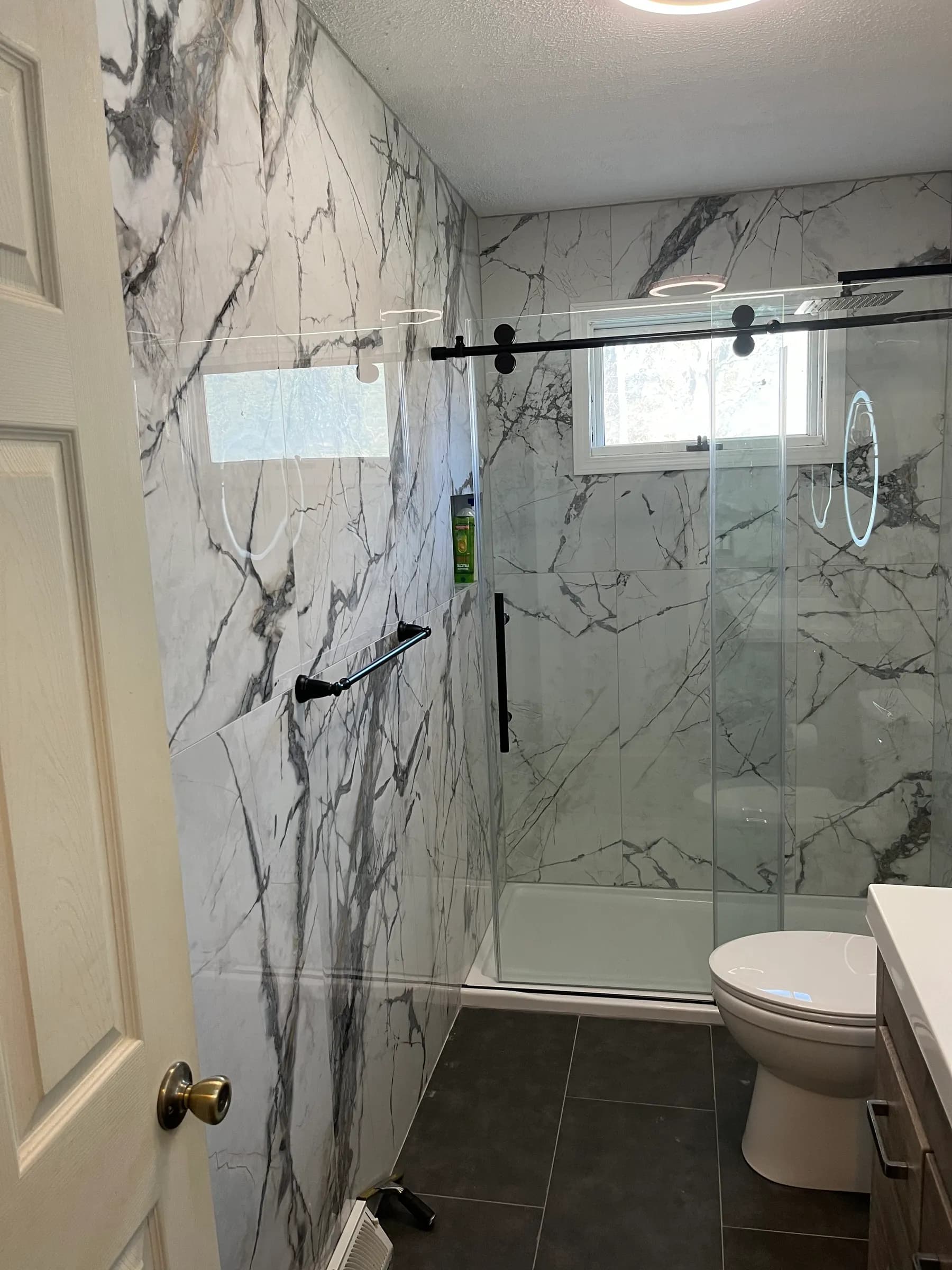 Marble walk-in shower with glass panel and marble floor